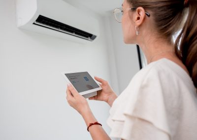 Pormenor de uma mulher com o comando digital de um aparelho de ar condicionado