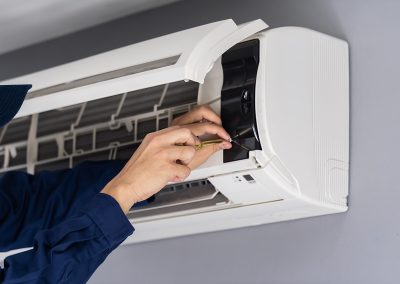 Pormenor de umas mãos a fazer manutenção de um aparelho de ar condicionado